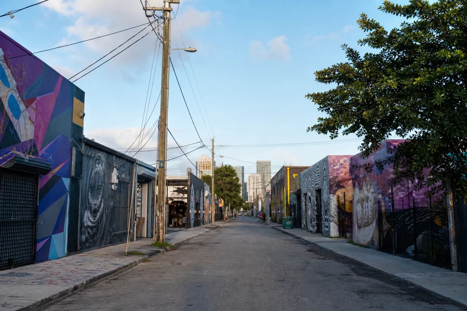 Quiet Wynwood street with colorful warehouse murals in morning light