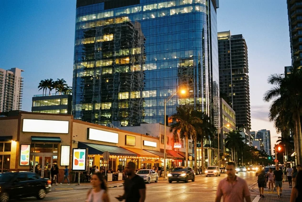 Glass towers rising over a street of restaurant frontages in the early evening