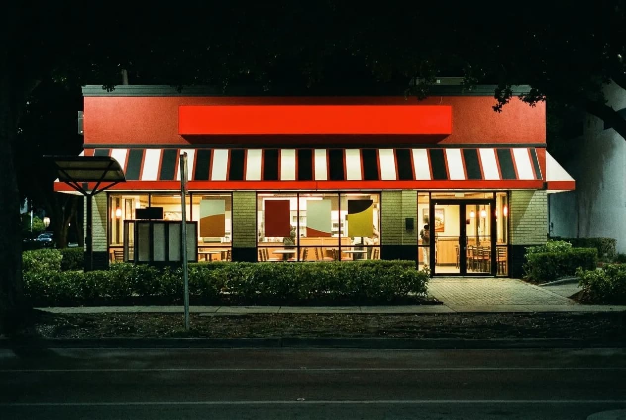 A lit dining room seen from an empty street on a night when little else is open