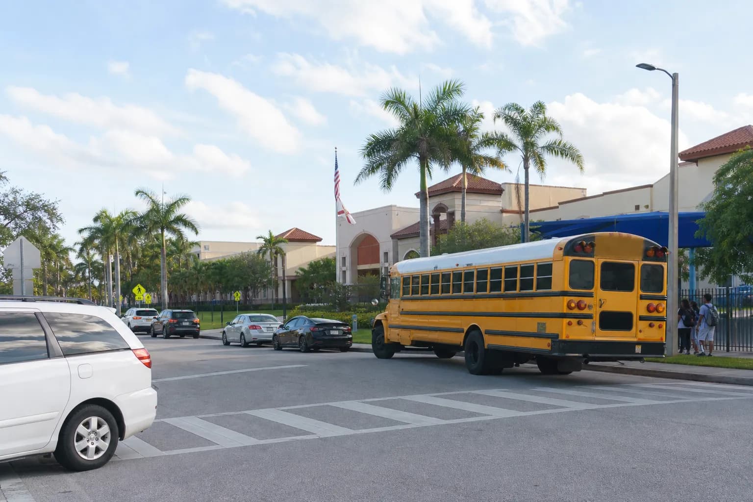 A Miami suburban school bus loading area with palms and wide lanes in Kendall