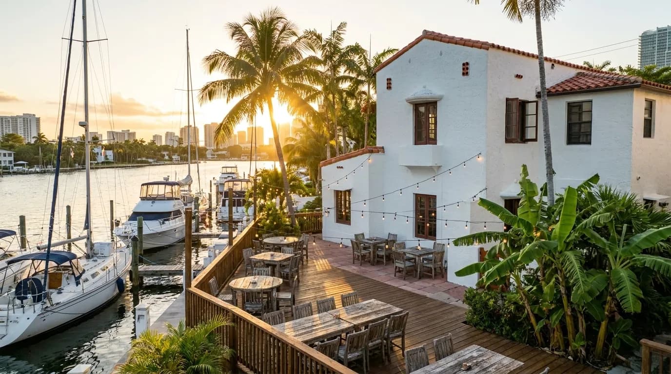 Outdoor waterfront dining area with boats docked alongside wooden deck at sunset in Miami