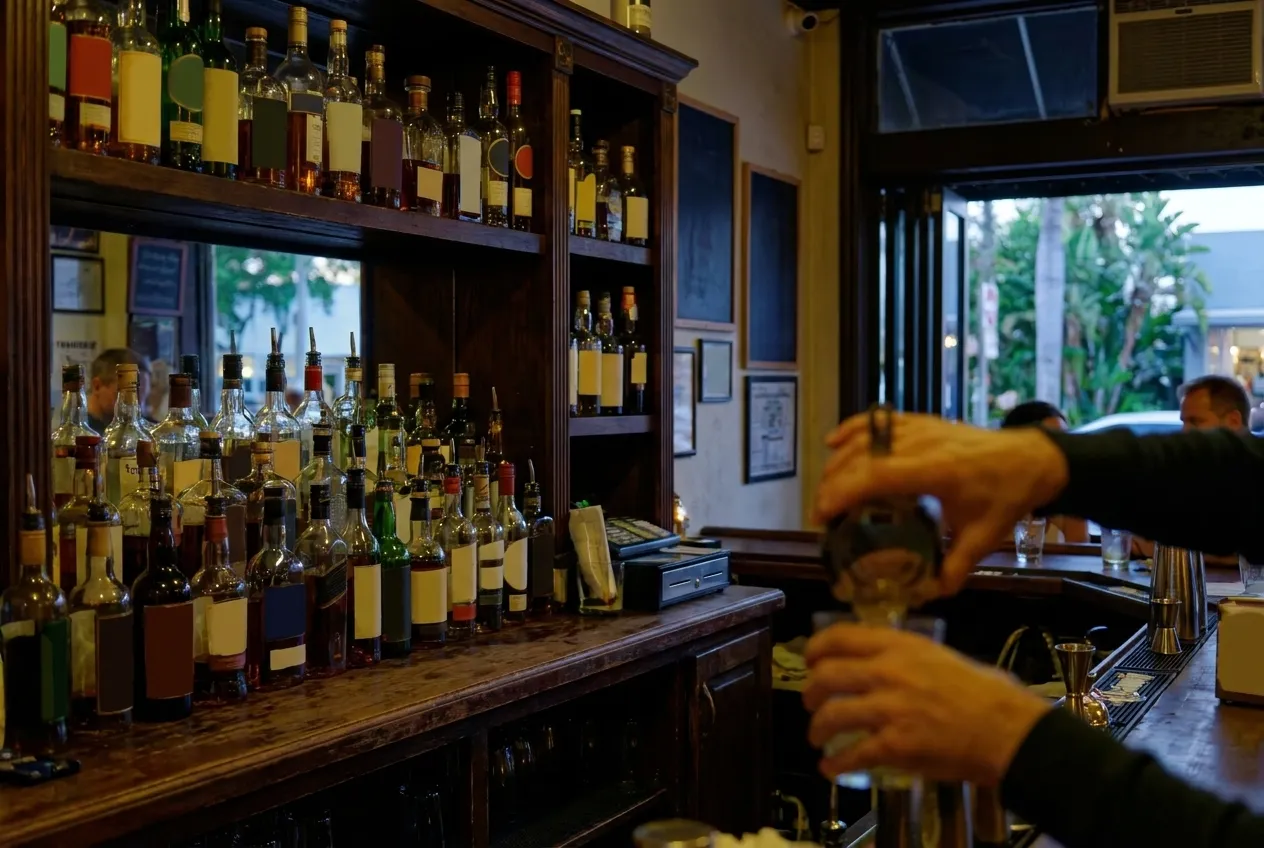 A small bar in the early evening, bottles ranked on shelves behind the counter