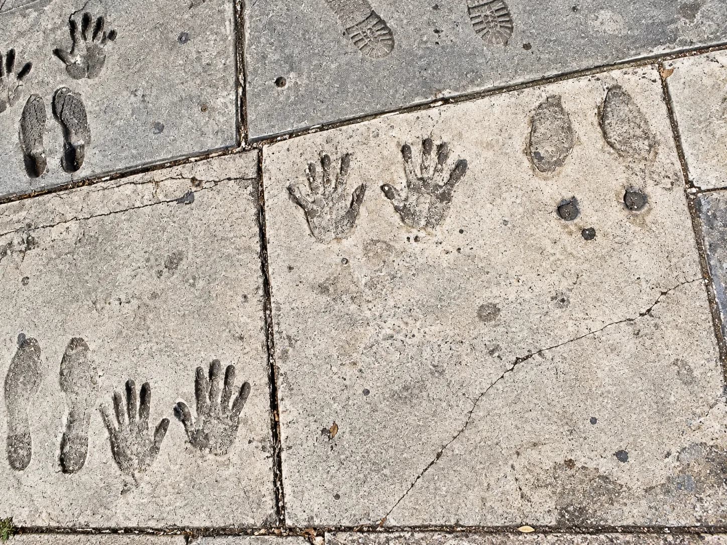 Squares of concrete paving marked with pressed handprints and signatures