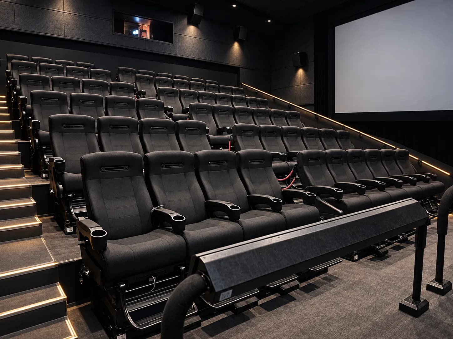 Empty cinema auditorium with tiered reclining seats on risers facing a wide blank screen and acoustic wall panels