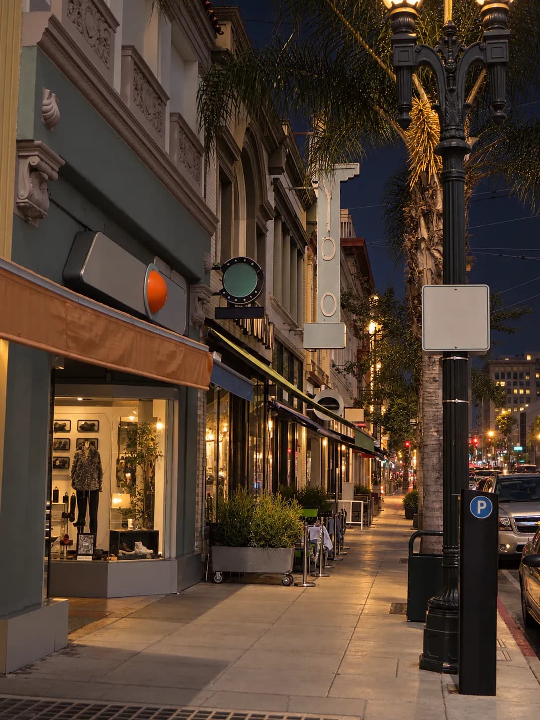Neighbourhood boulevard at night with low storefronts and a vintage vertical theatre marquee left unlit and blank