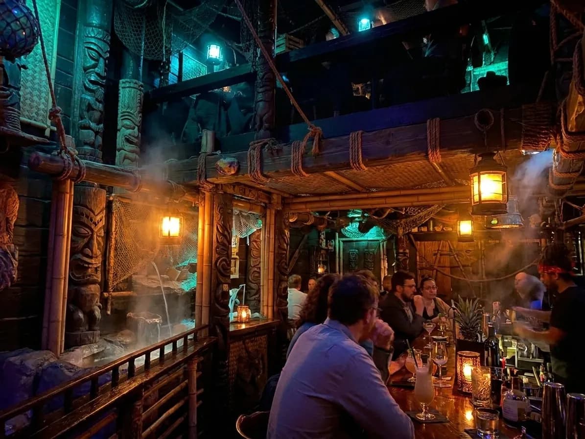 Multi-level tiki bar interior with bamboo details, nautical artifacts, and dim atmospheric lighting at Smuggler's Cove in Hayes Valley