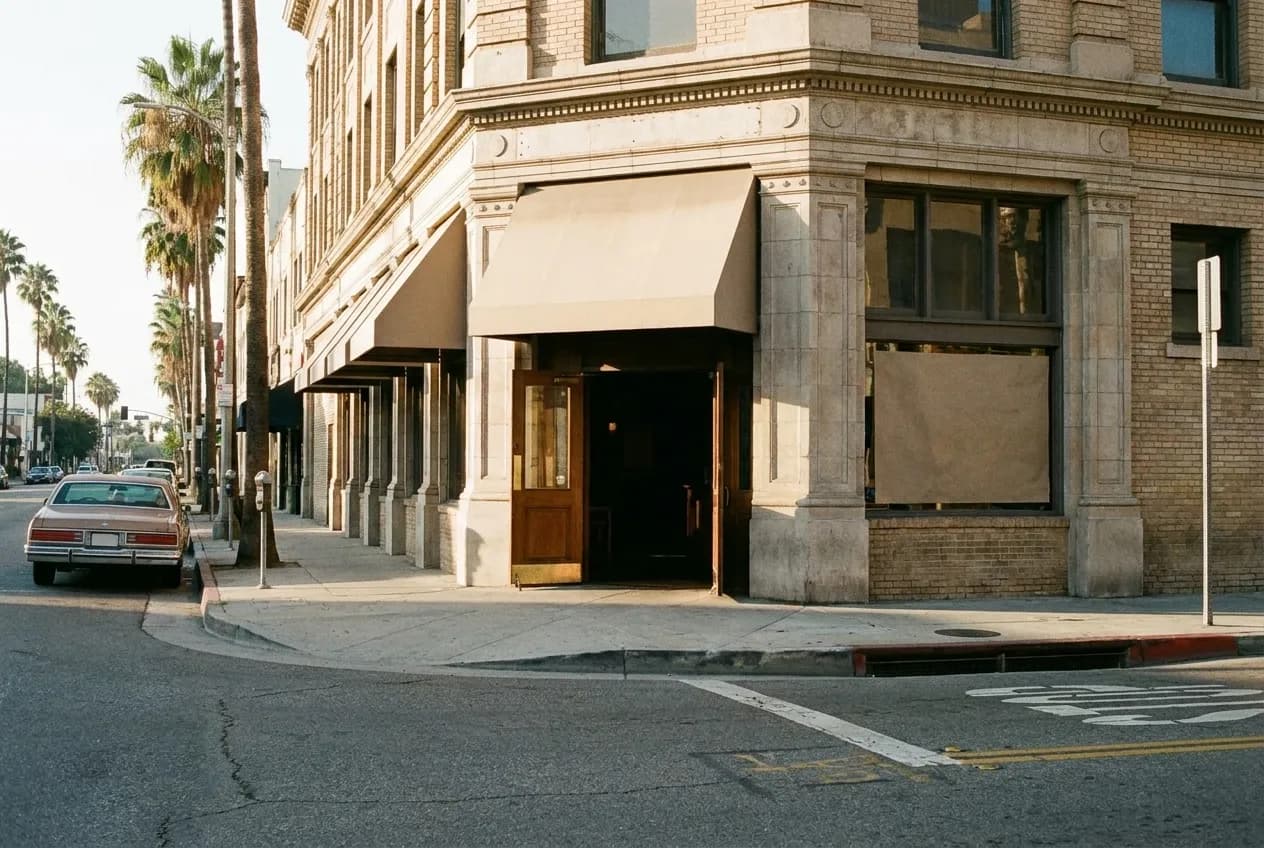 The lit facade of a corner pub in Los Angeles in the early morning with the door propped open
