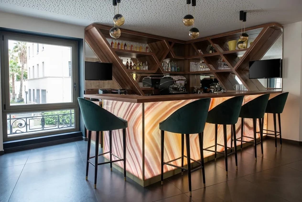 A wide bar room with multiple screens and empty stools before opening
