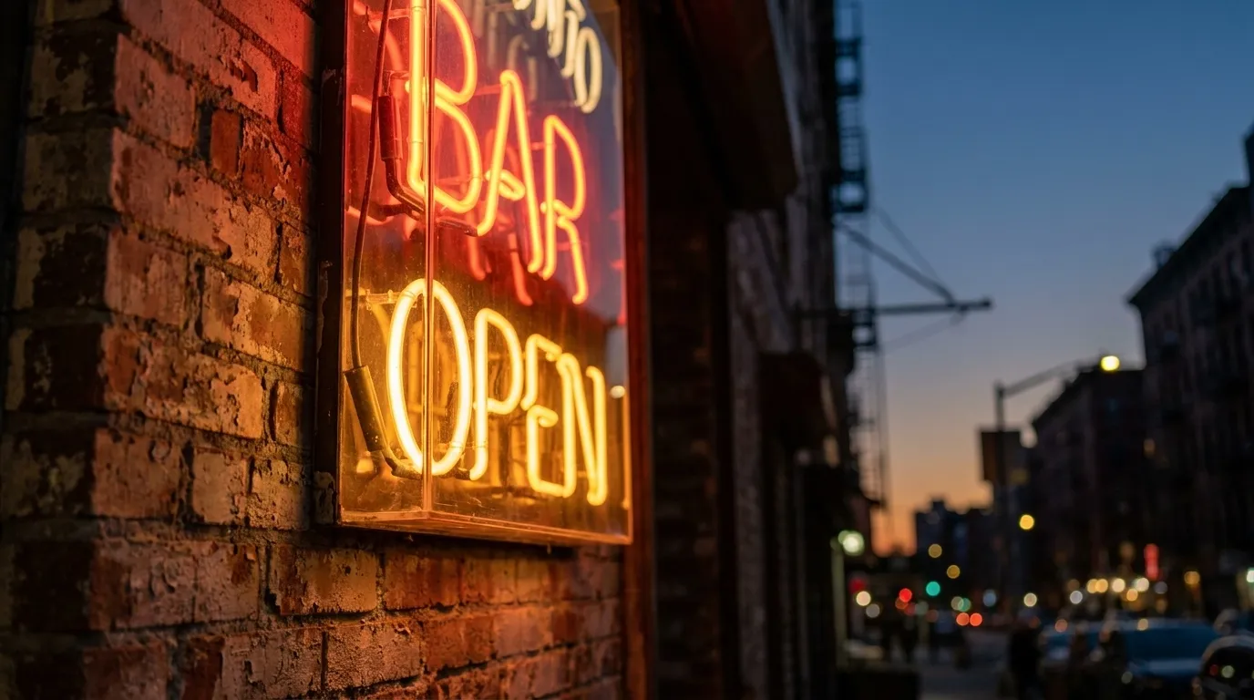 Neon bar sign glowing against brick wall on Rivington Street in the evening