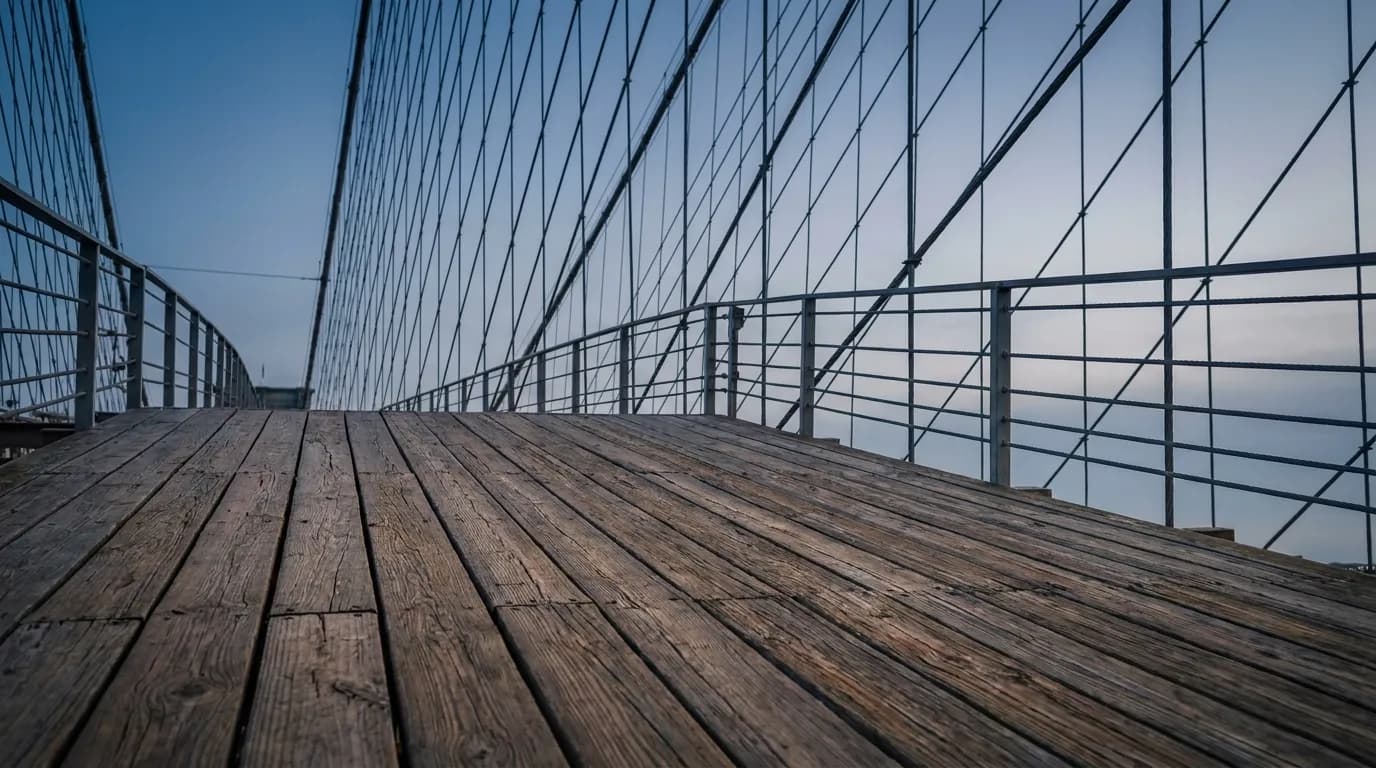 Wooden planks and steel cables on the Brooklyn Bridge pedestrian walkway at dusk