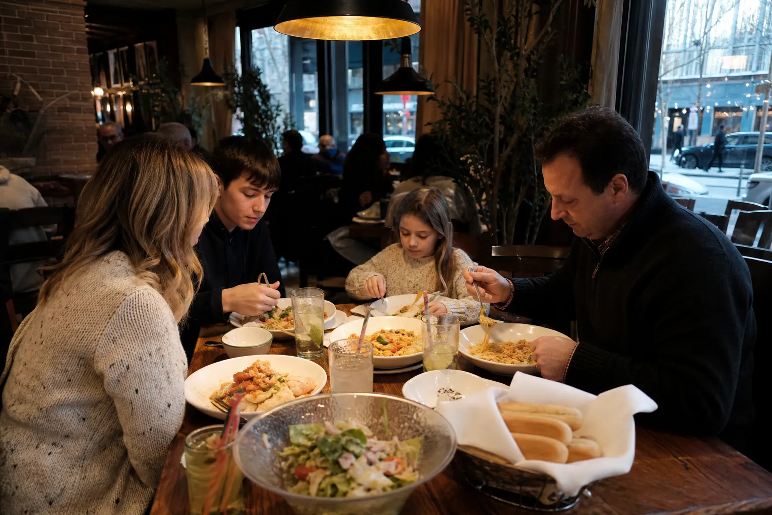 A warm, inviting table setup with pasta, salad, and breadsticks at the Chelsea Olive Garden location.