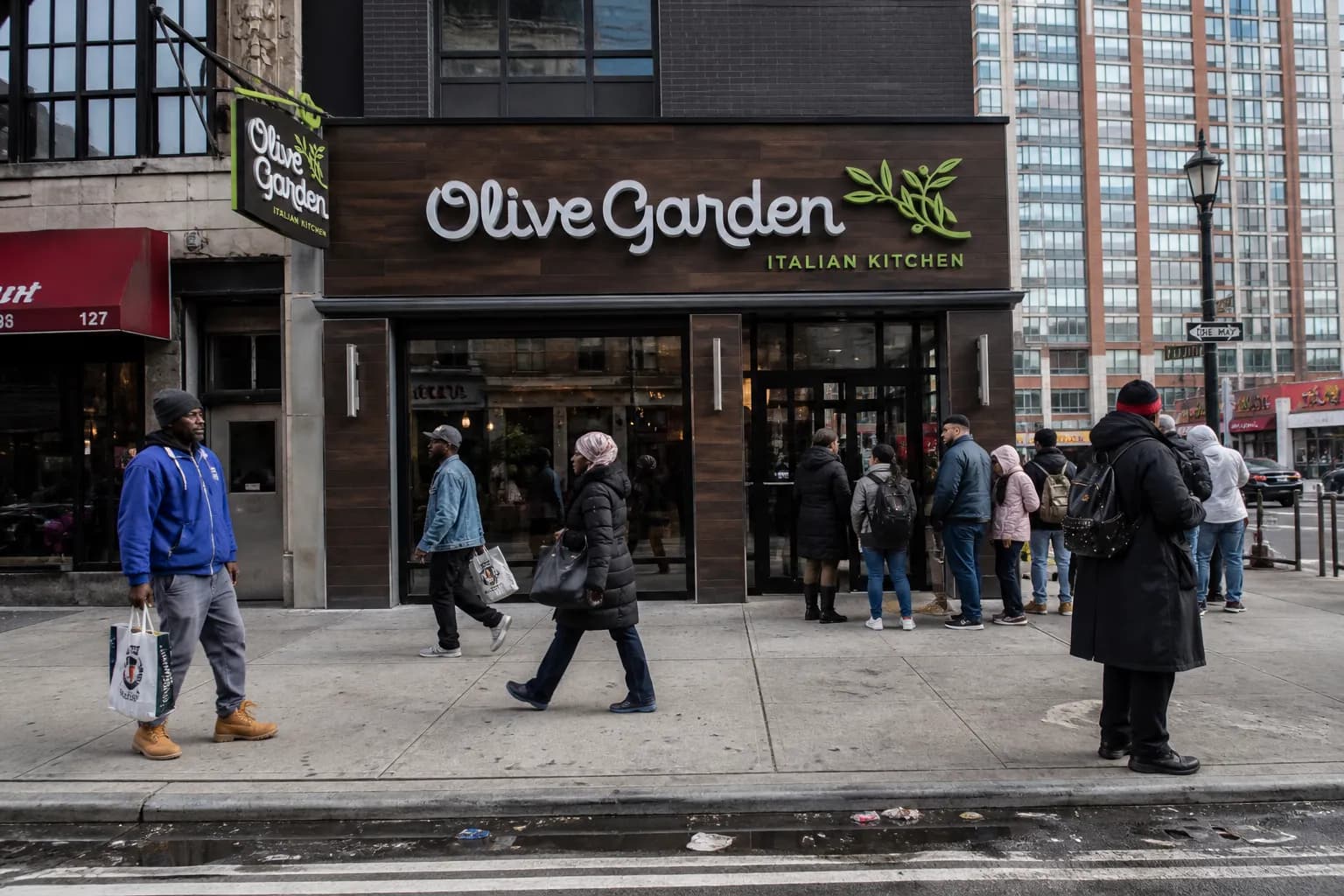 The modern storefront entrance of the Olive Garden on 125th Street in Harlem, NYC.