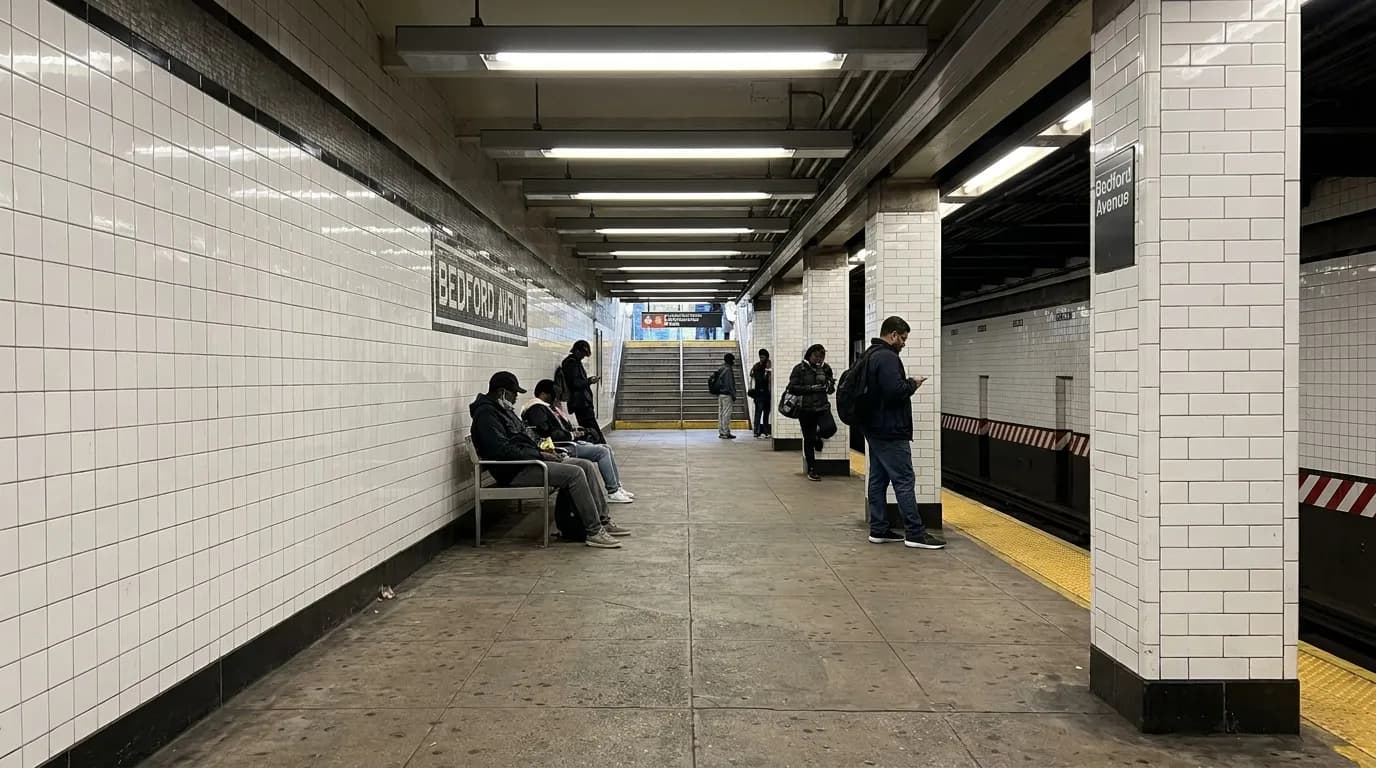 The Bedford Avenue subway platform on the L train in Williamsburg, with tiled walls and commuters waiting in late afternoon light.