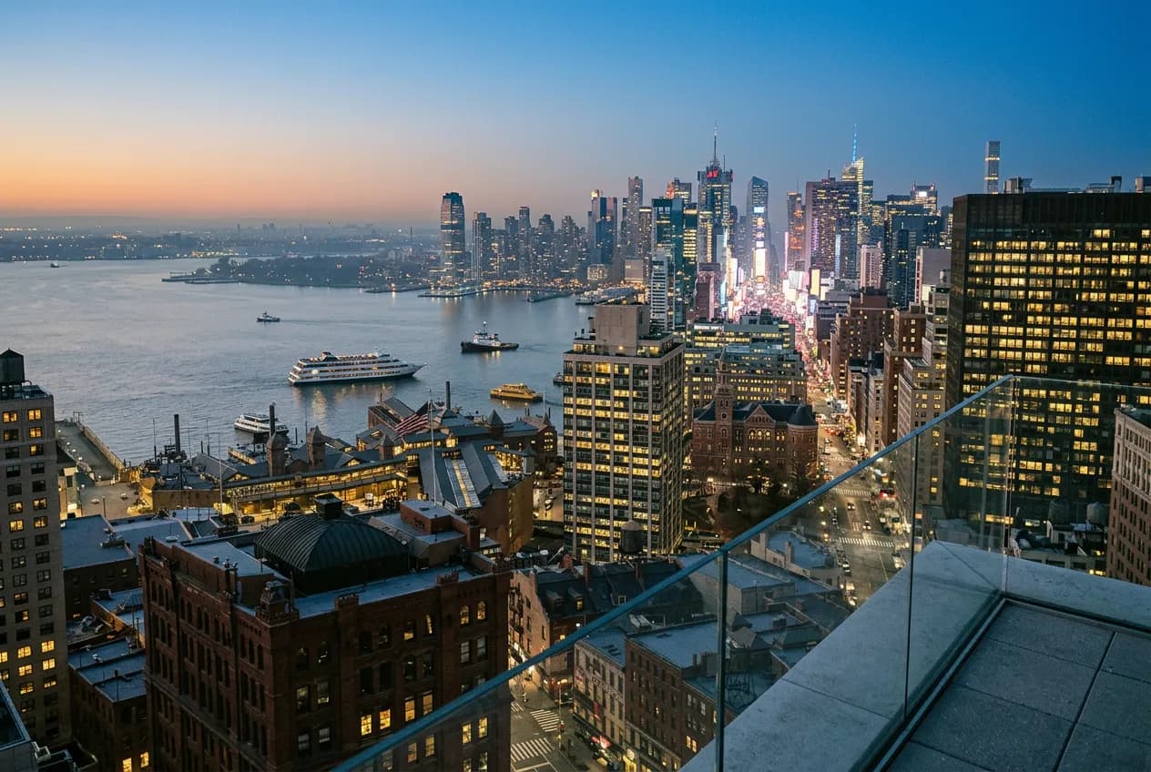 Midtown Manhattan skyscraper facades glowing at dusk seen from a high rooftop vantage near Times Square