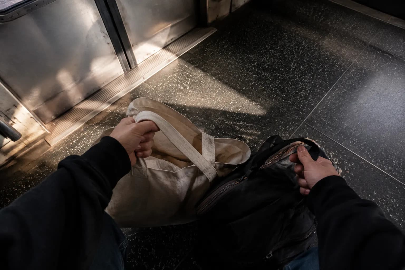 Hands holding reusable shopping bags on a New York City subway car