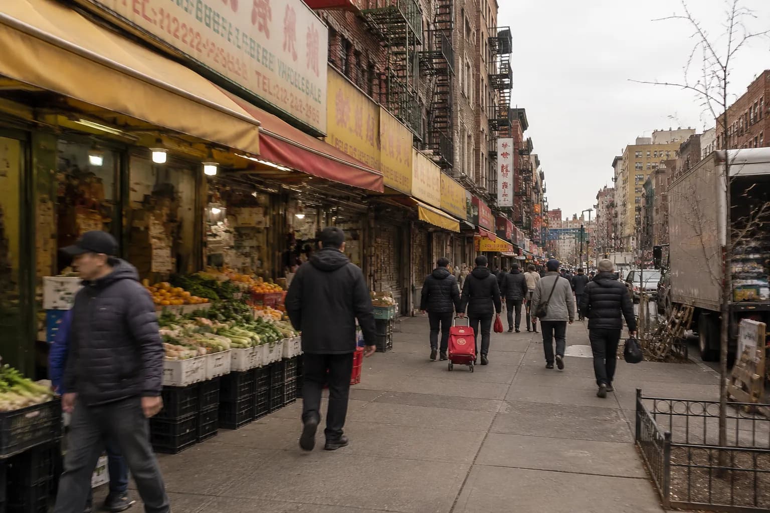 Canal Street sidewalk in Chinatown on a weekend morning, with produce vendors and pedestrians