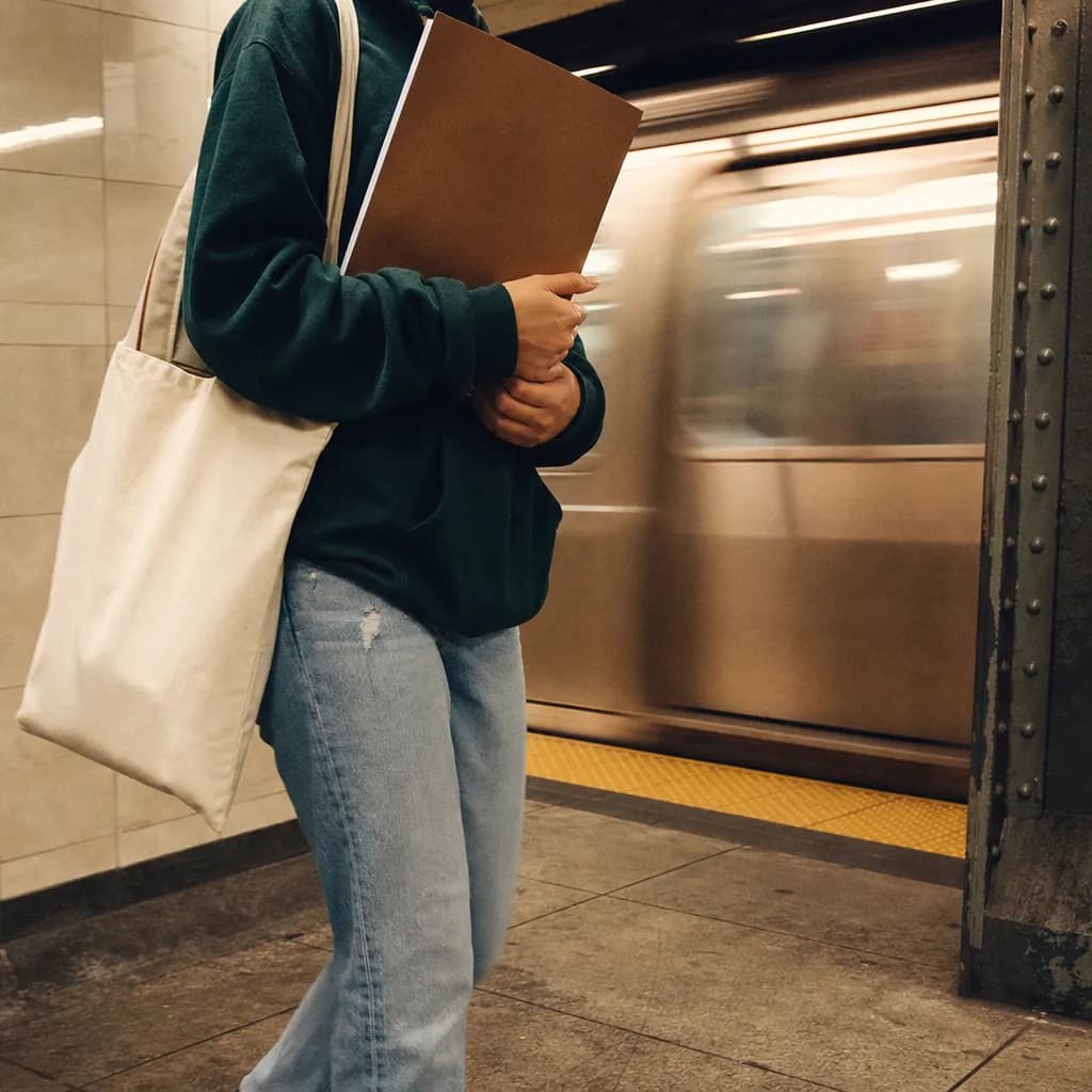 A late afternoon subway transfer with a student holding a campus folder