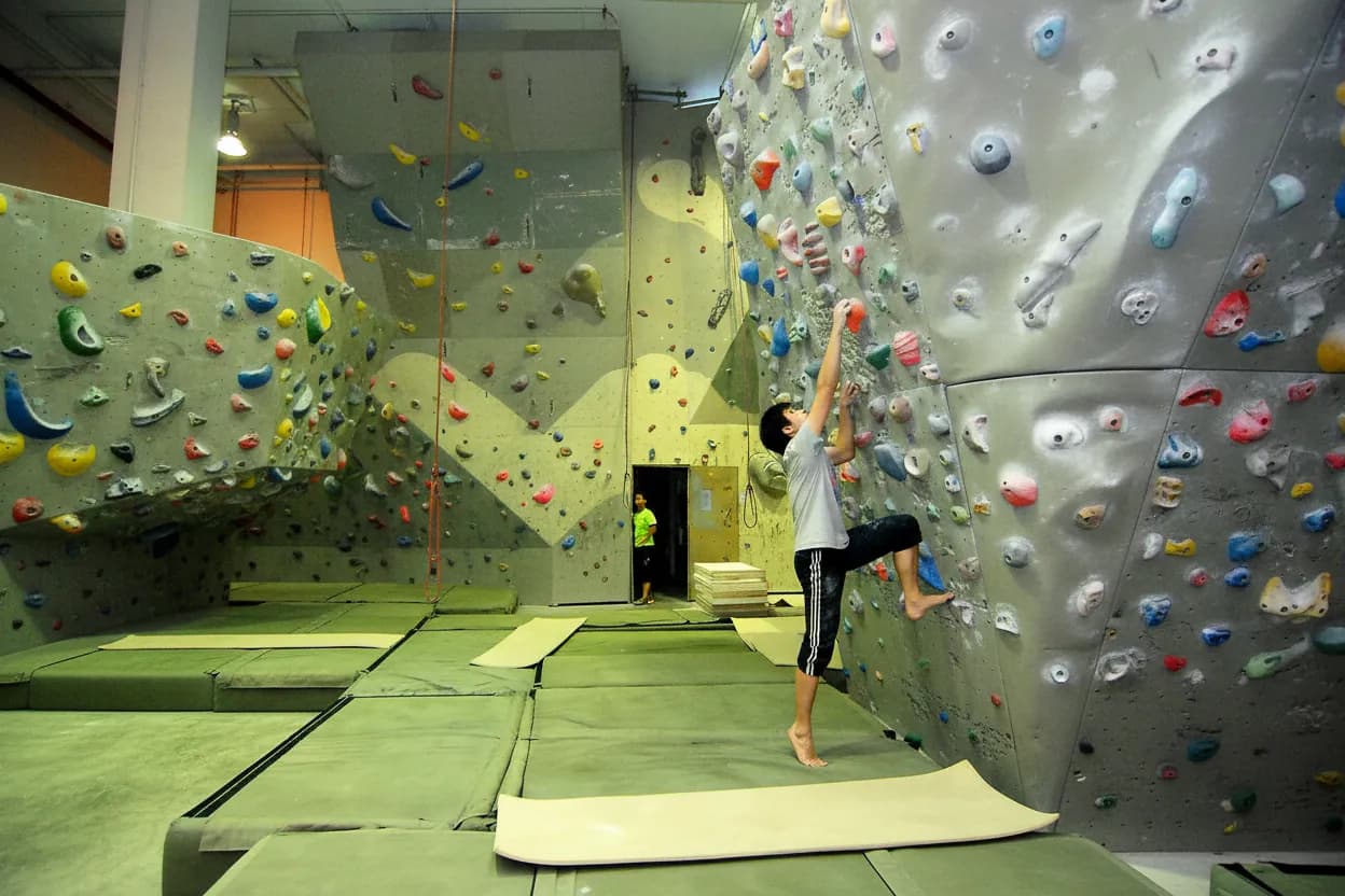 A beginner reaching for a hold on an indoor climbing wall