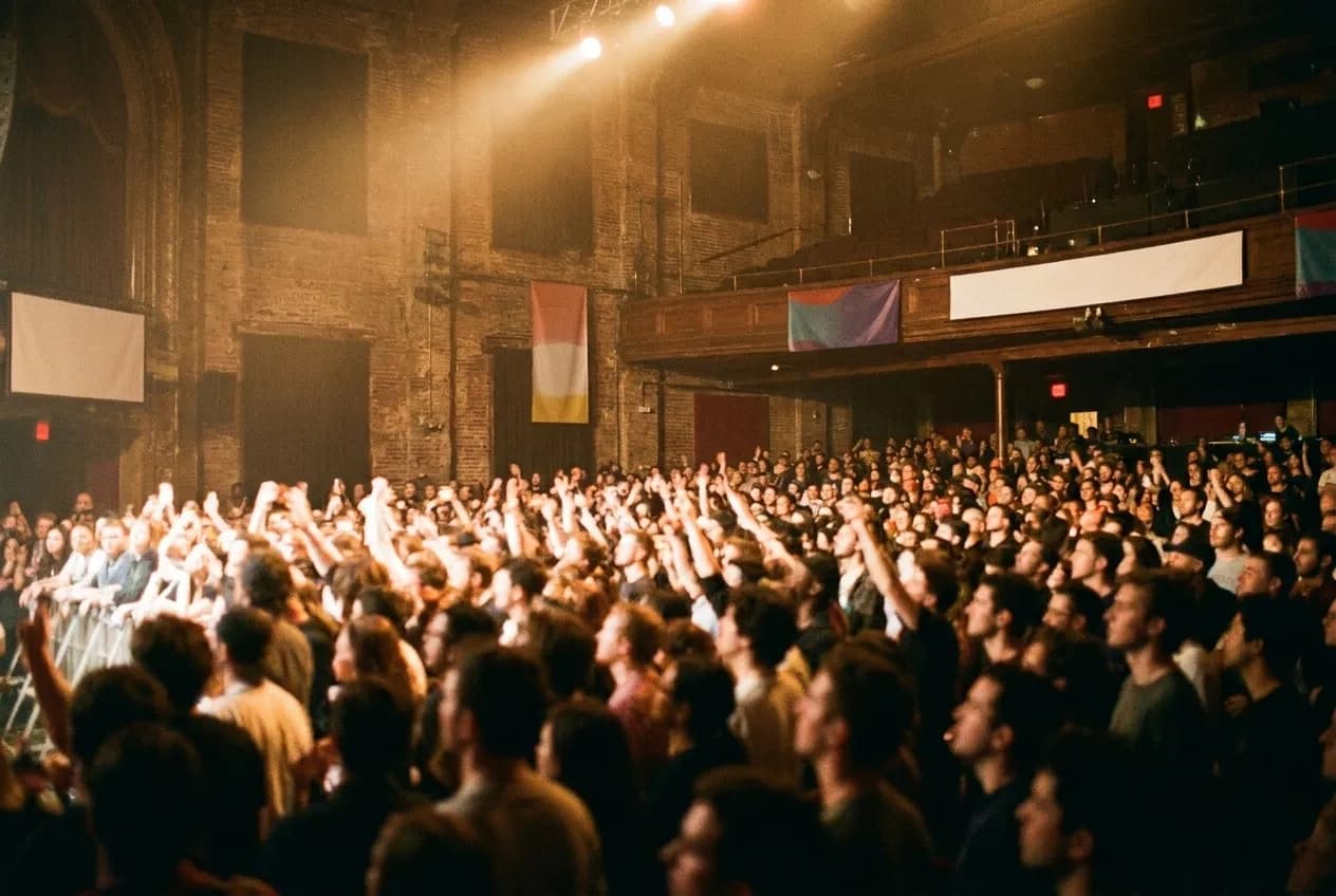 Stage light spilling over a packed floor in a mid-size music hall