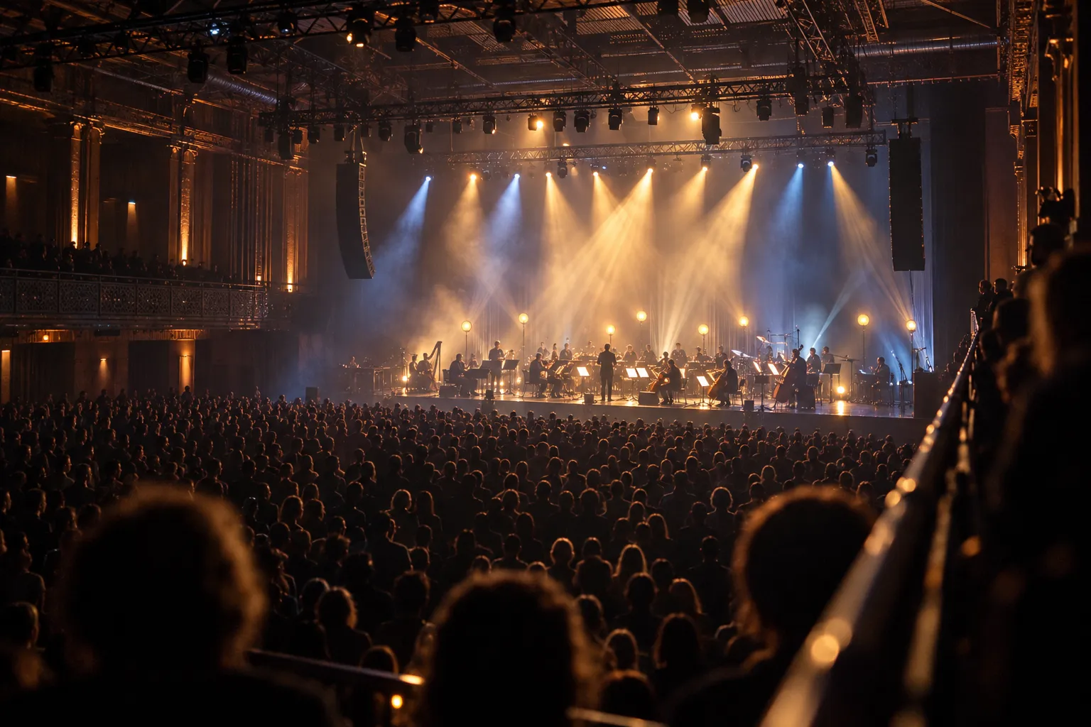 A large dark concert hall with a lit stage seen from a balcony