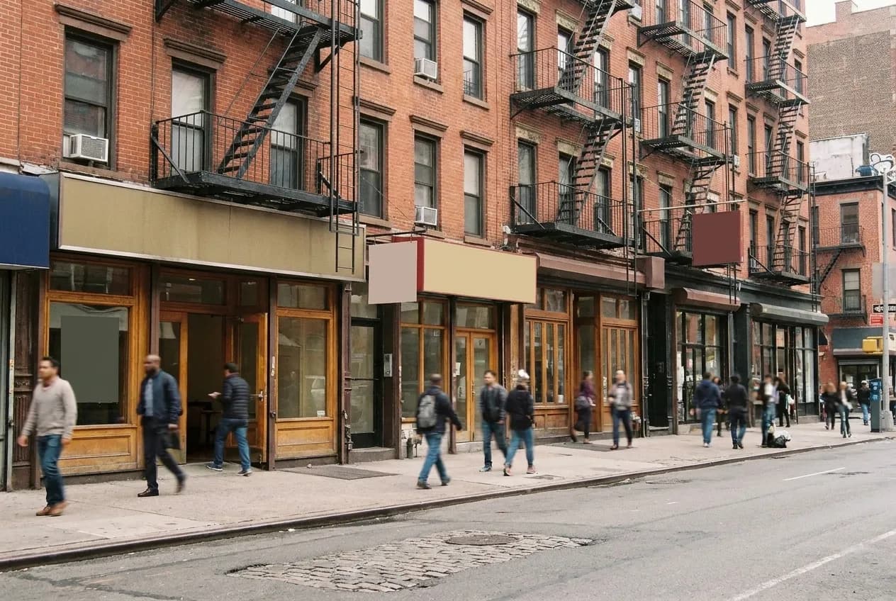 A Lower East Side block on a Saturday afternoon, people moving between storefronts
