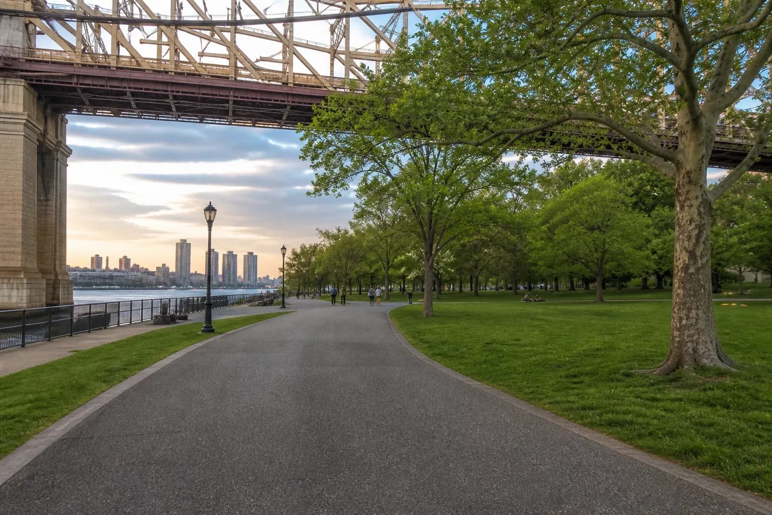 Wide view of Astoria Park with river air, bridge, and open lawn