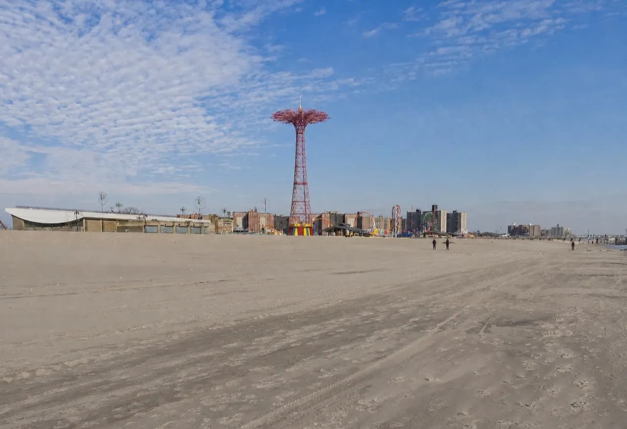 Wide empty stretch of city beach with the boardwalk behind