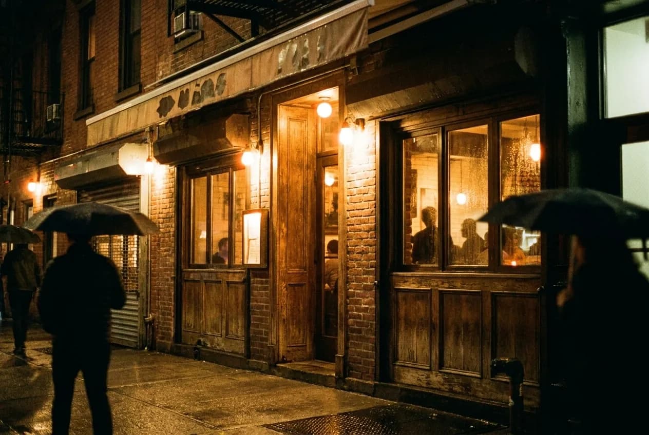Lit restaurant storefront on a Manhattan side street after dark