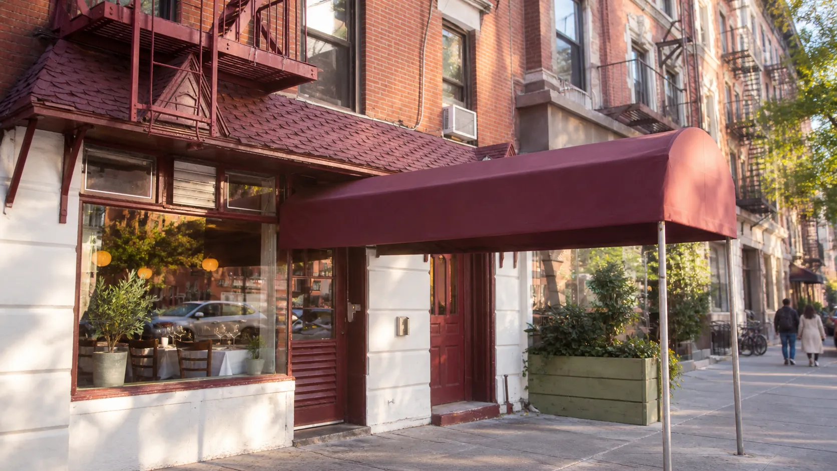 Whitewashed narrow corner restaurant on Canal Street with pastel accents, pale masonry and late-afternoon light, shown without lettering or faces.