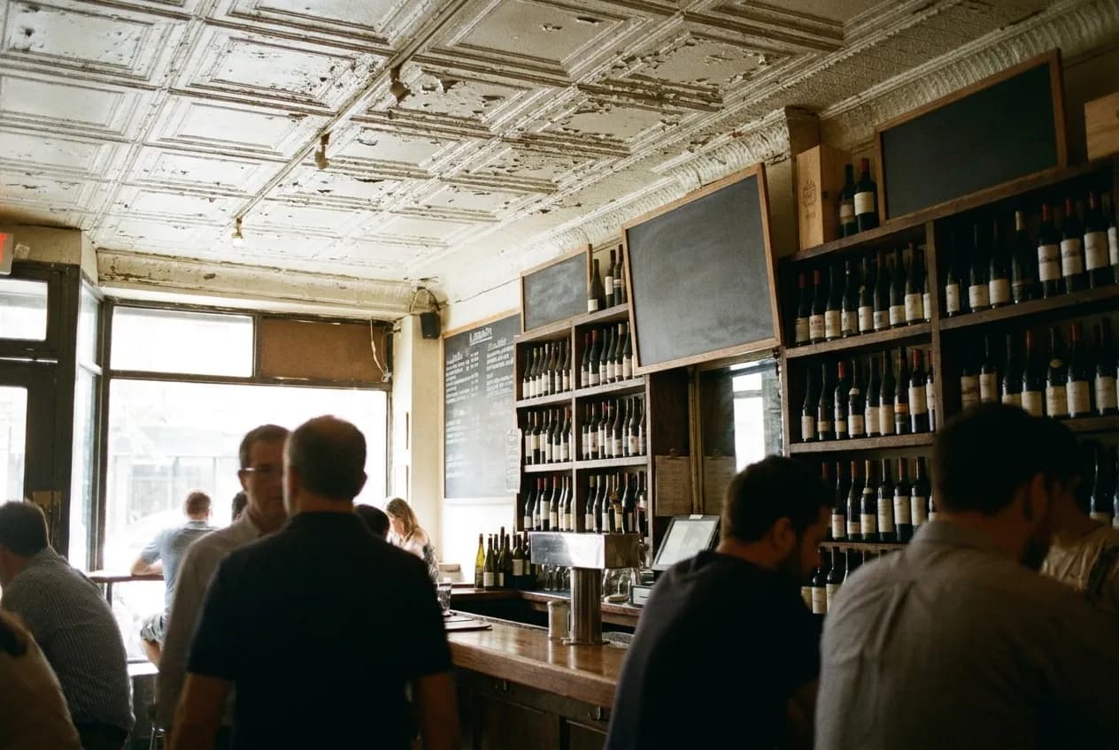 A narrow wine bar under a pressed-tin ceiling, bottles racked behind the counter