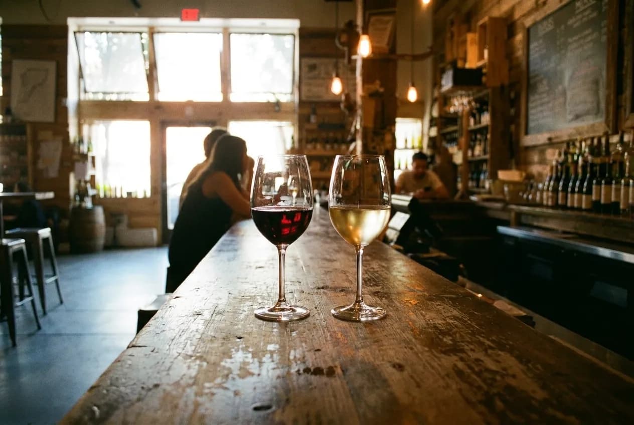 Two glasses poured side by side on a worn wooden bar