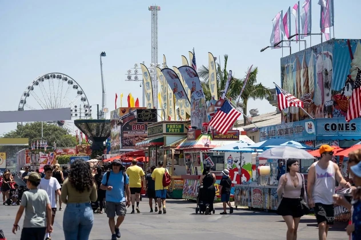 Wide view of the OC Fair midway with rides and fairgoers in Costa Mesa