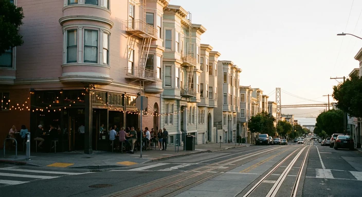 Golden hour light down a steep San Francisco street with string lights glowing at a corner bar