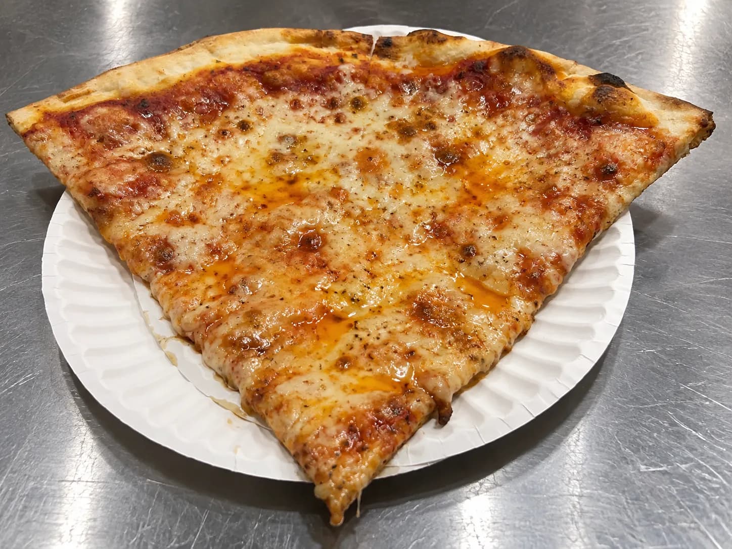 A single slice of cheese pizza folded on a paper plate