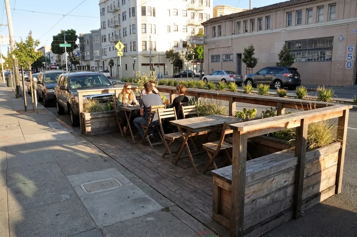 A wooden parklet dining structure on a city street in afternoon sun