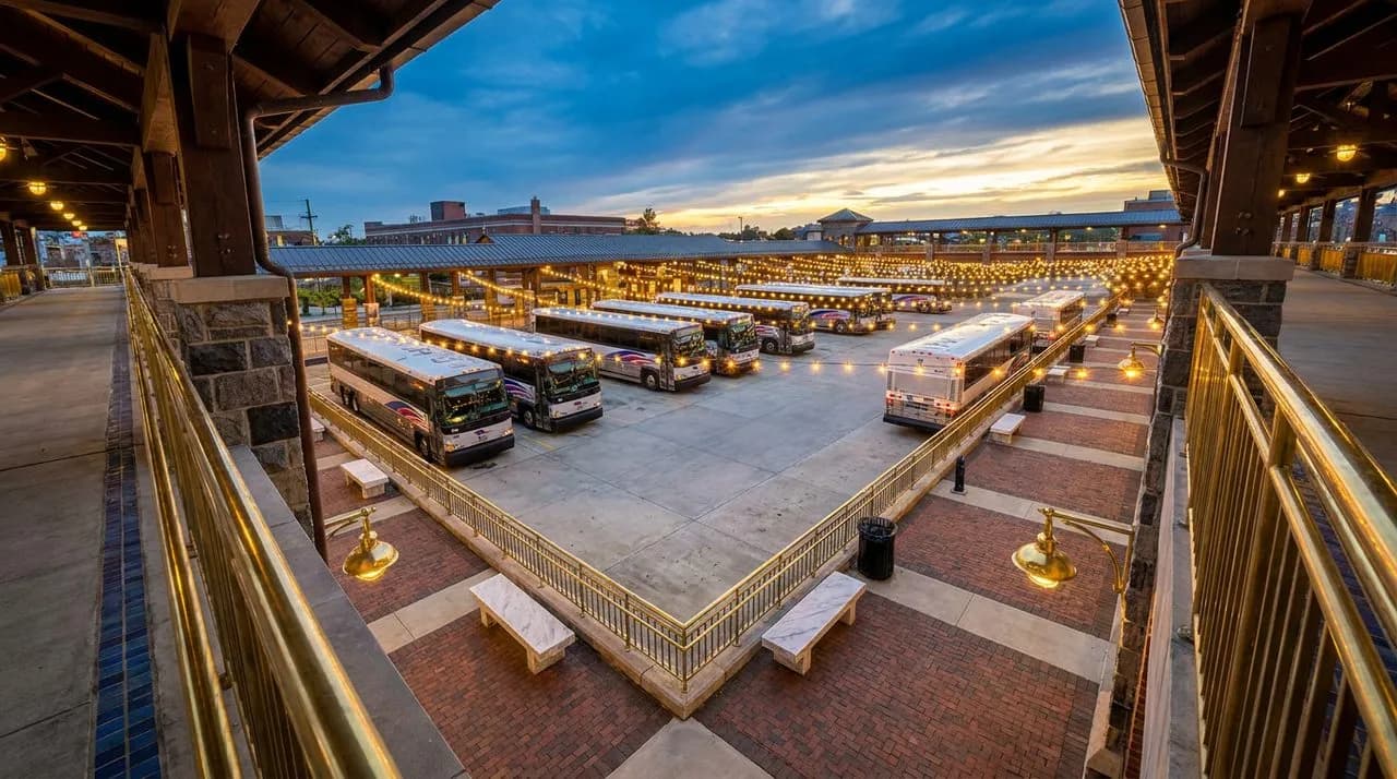 Bright early-evening overhead view of NJ Transit bus plaza near MetLife after WC 2026 match, rows of polished coach buses, concrete plaza, brass railings, festoon lights, vivid sky, no people