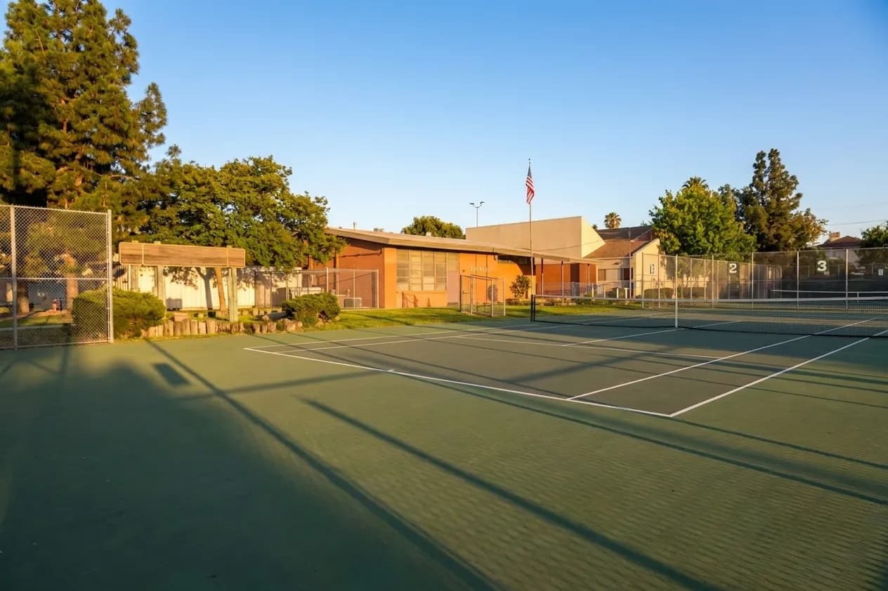 Wide view of six lighted tennis courts at Penmar Recreation Center in Venice, with oversized court numbers visible on green hard surfaces