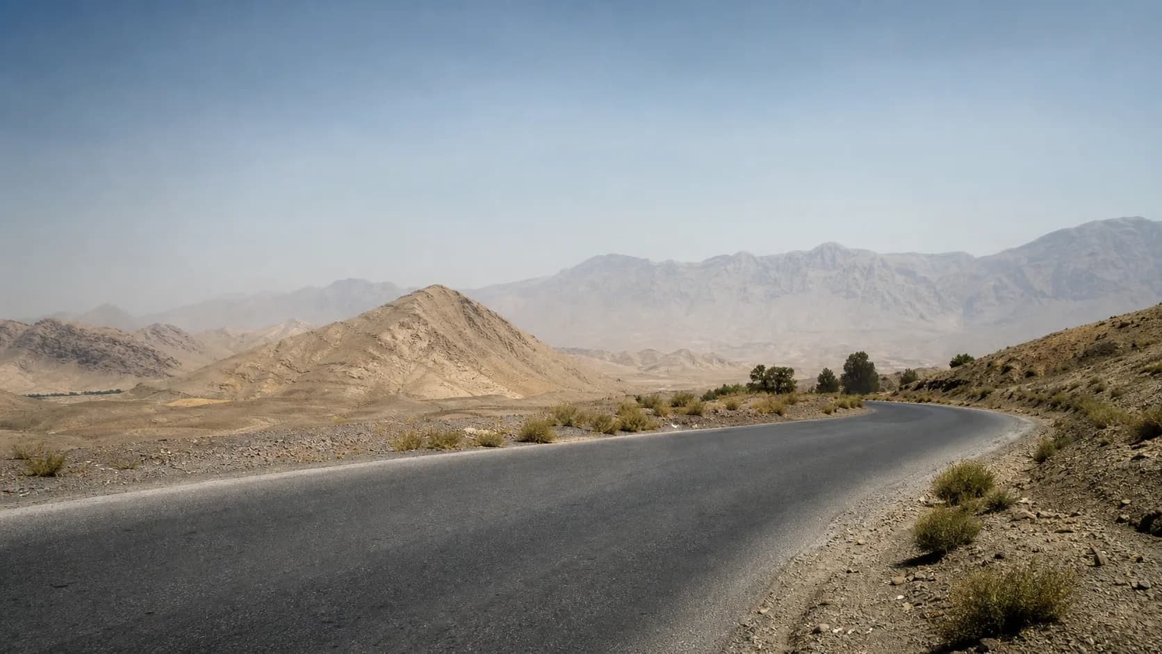 An arid mountain landscape in Iran viewed from a quiet road.