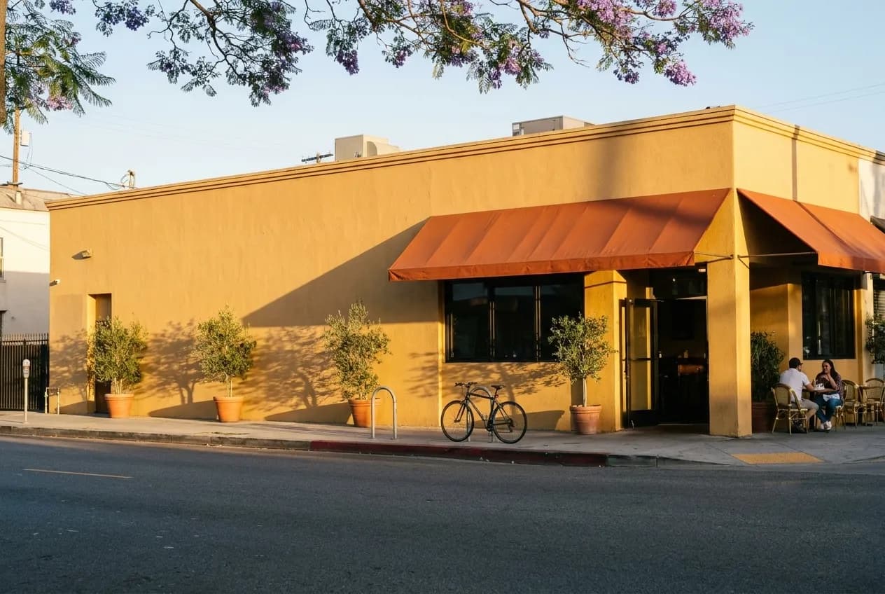 A bright yellow corner restaurant building with an orange canopy on a Los Angeles boulevard