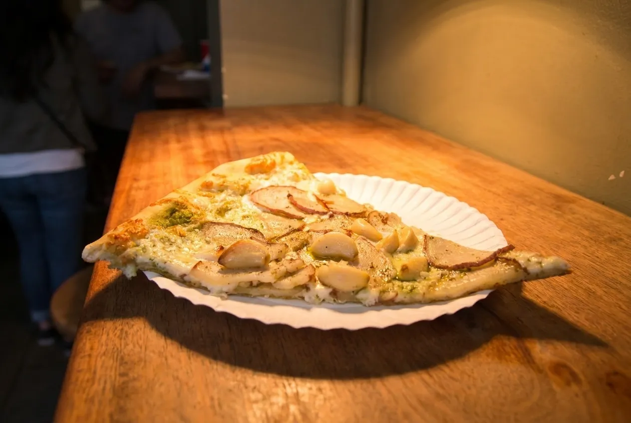 A single slice on a paper plate under a heat lamp