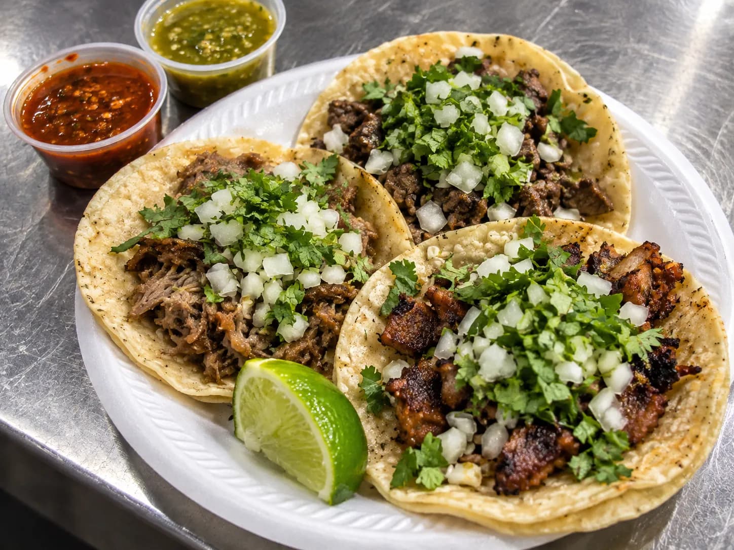 A paper plate of tacos with salsa and radish on a market counter