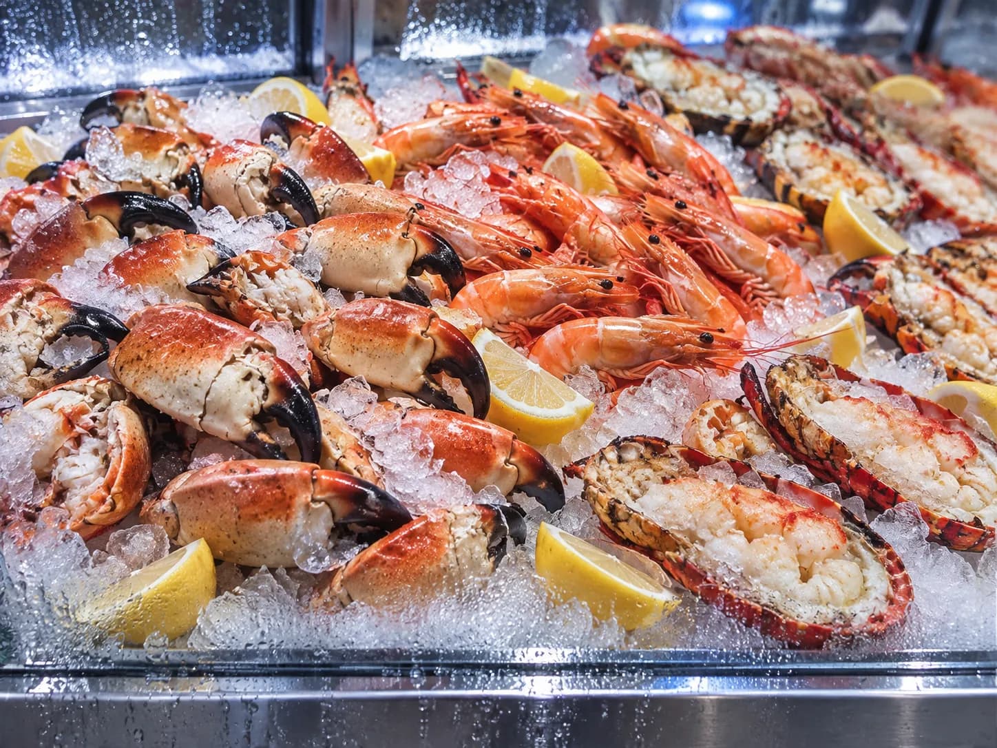 Cracked crab and shrimp arranged on shaved ice behind glass