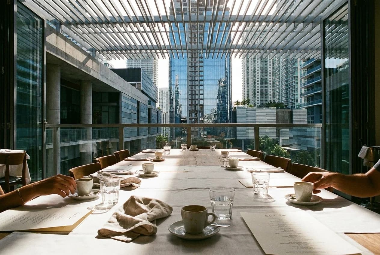 Communal table at Casa Tua Cucina food hall inside Brickell City Centre with espresso cups and morning light