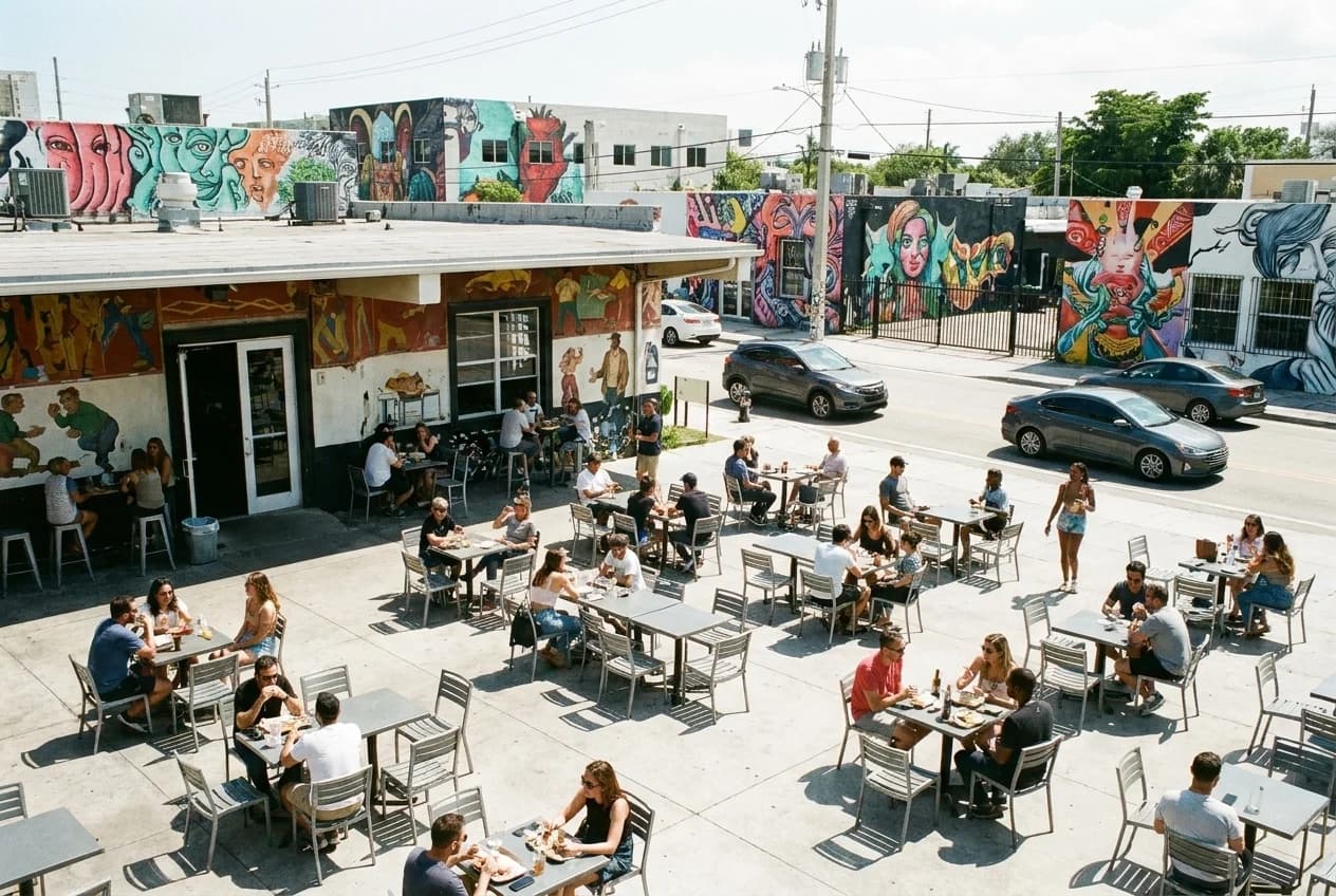 Outdoor terrace seating at Wynwood restaurant with metal chairs and street art-covered walls in background