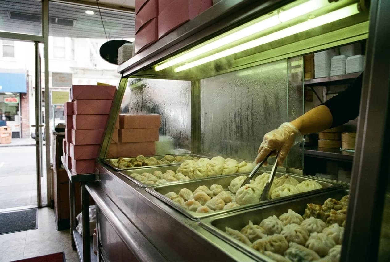 Steam trays of dumplings and buns behind a neighborhood bakery counter