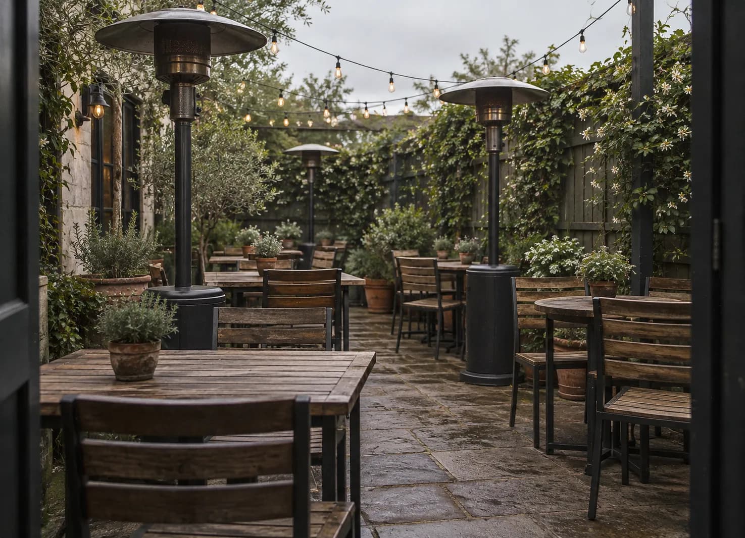 A small heated garden patio with wooden tables and heaters