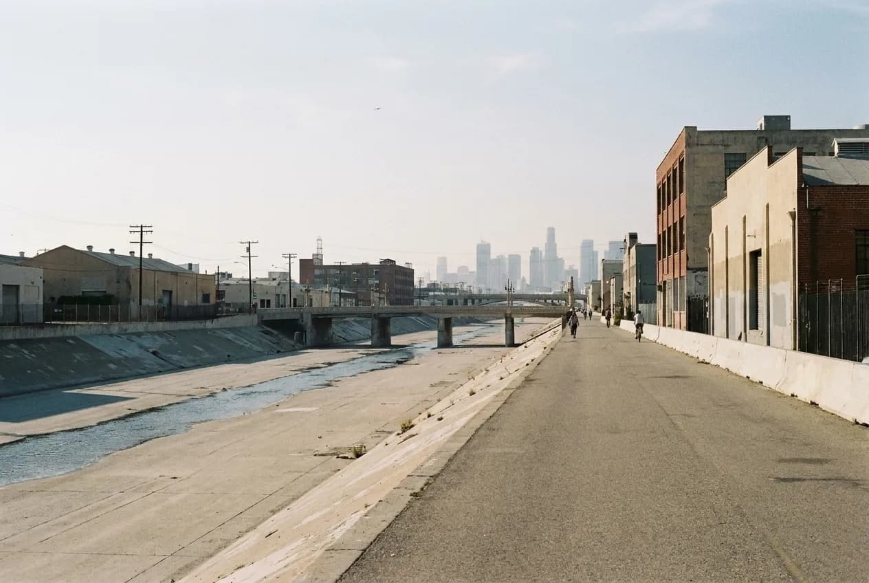 A concrete river channel with a paved path and industrial buildings alongside in Los Angeles