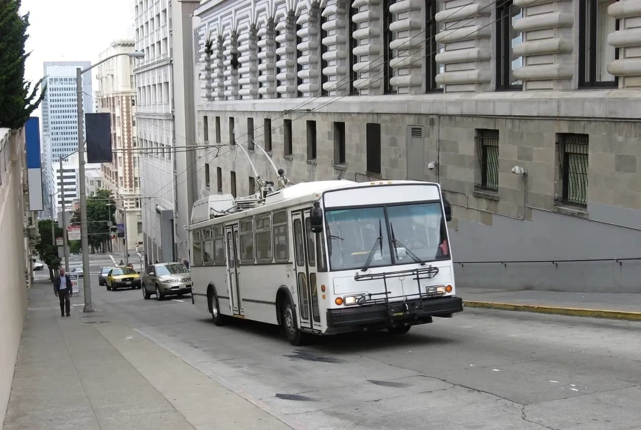 A steep city street of apartment buildings dropping downhill toward the bay in San Francisco