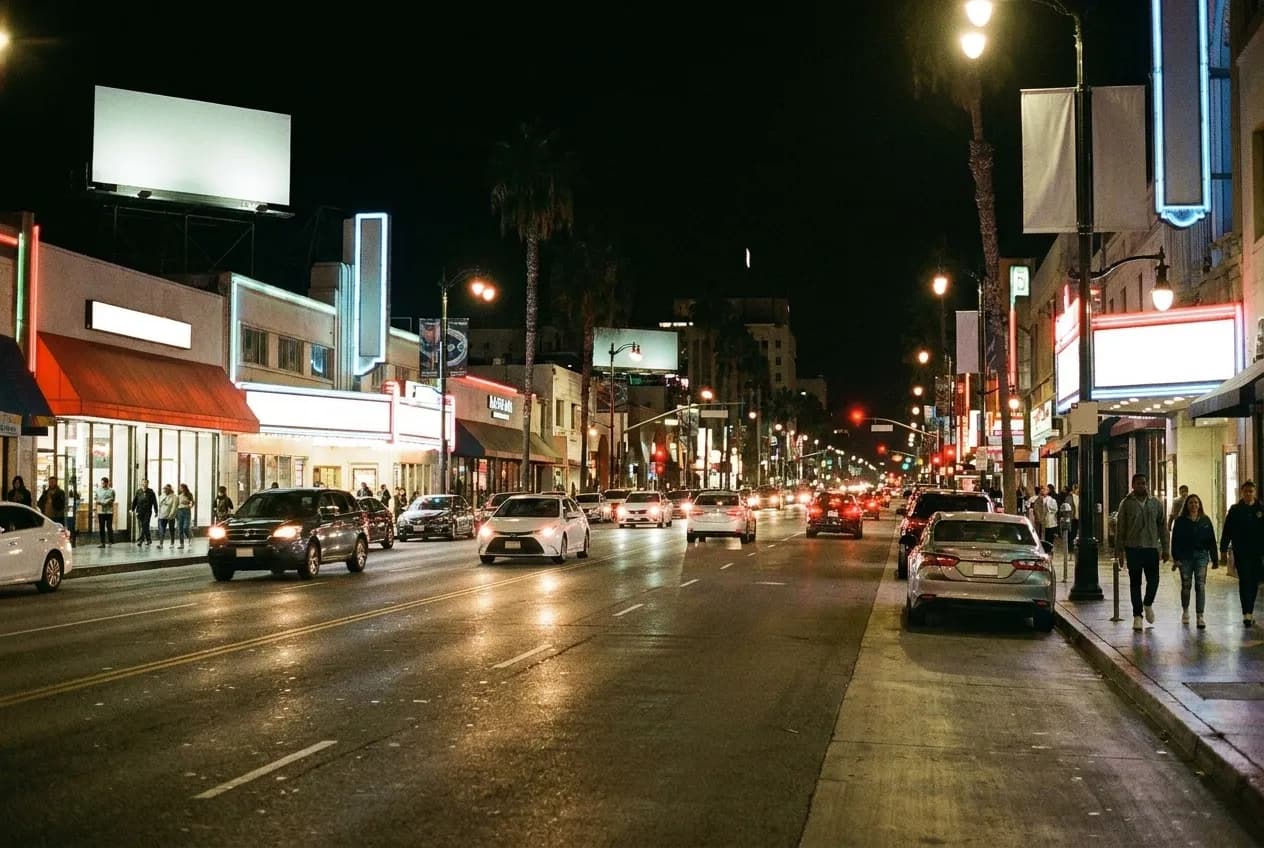A wide Los Angeles boulevard at night with lit signs and light traffic