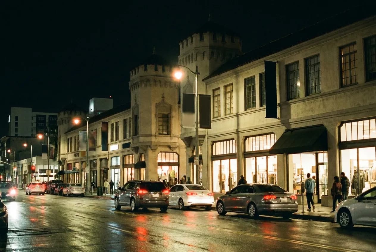 A Los Angeles street at night with two-storey plaza buildings and lit windows